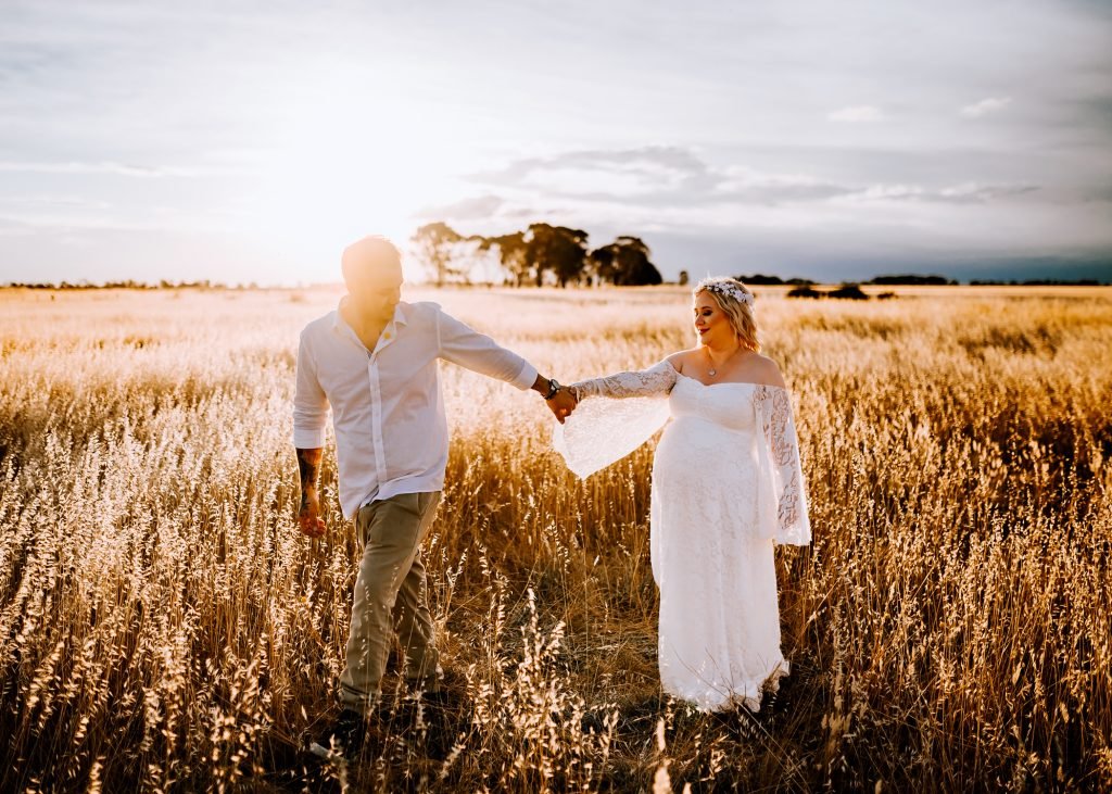 Field maternity session in soft sunset light